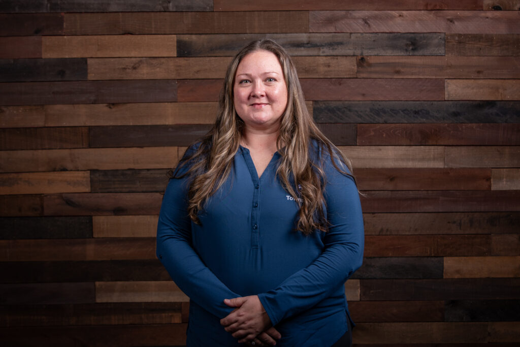 woman with a blue button up shirt in front of a wooden background