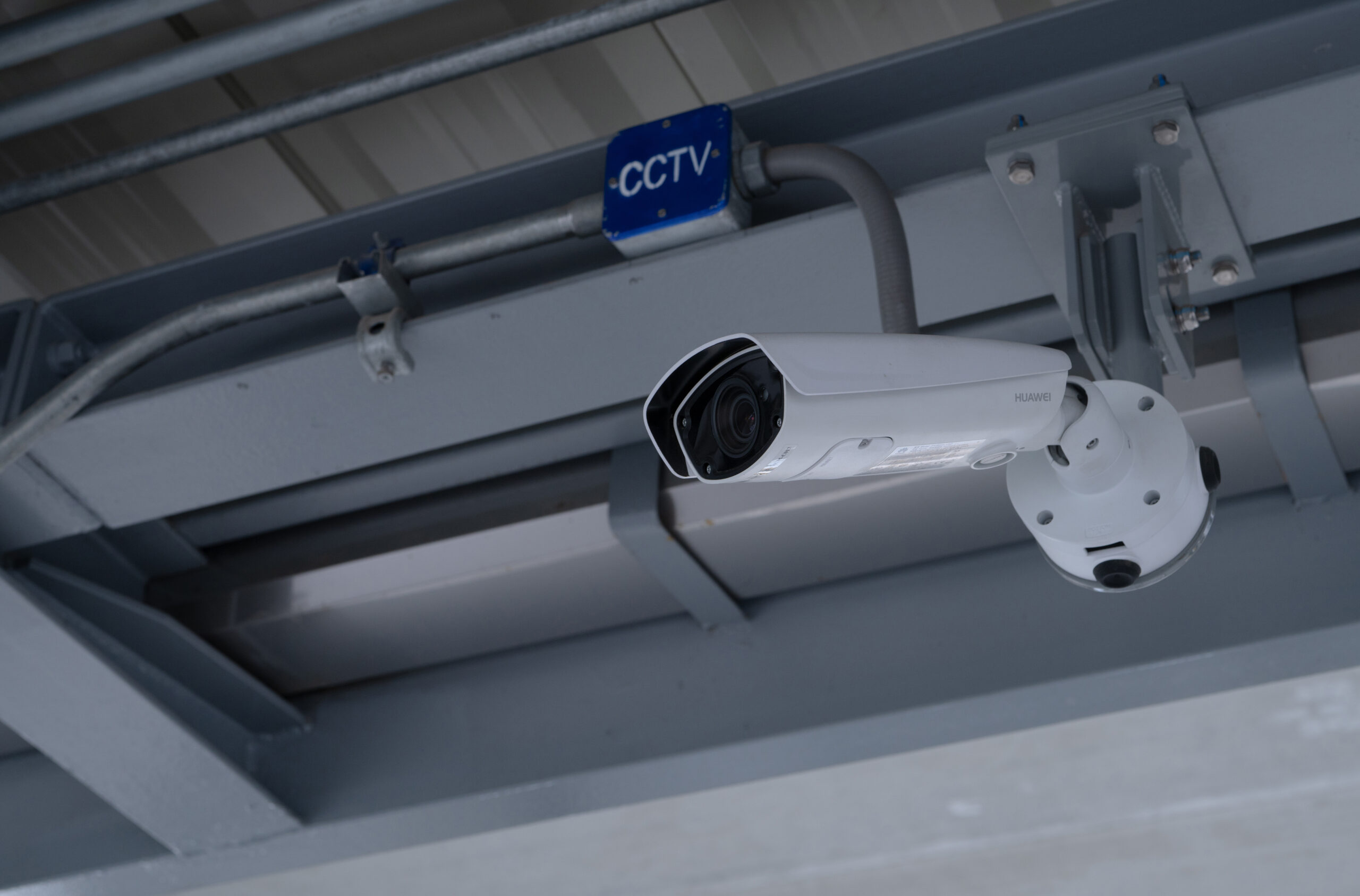 close up of a white security camera mounted on a silver ceiling