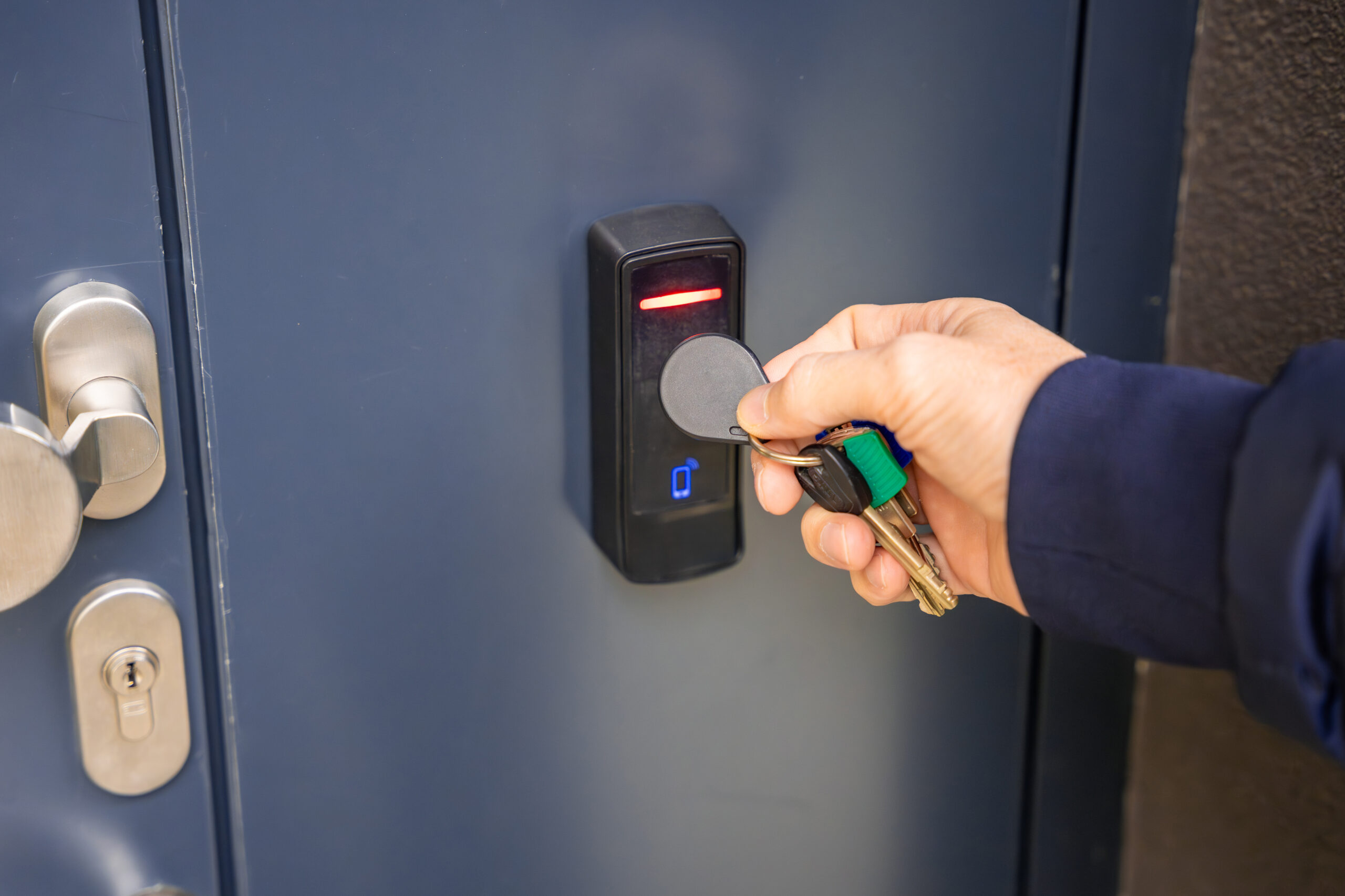 close up of a hand holding a key fob up to a black key fob detector on a navy blue locker