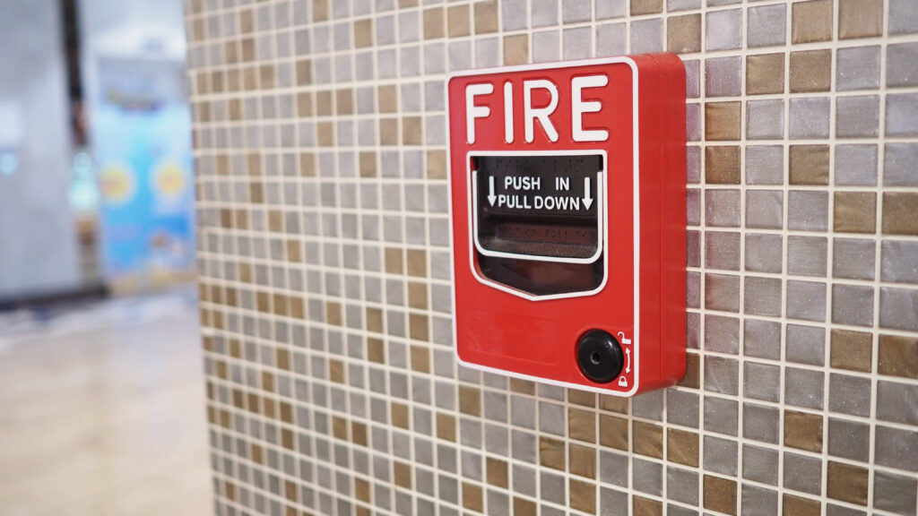 Red Fire Alarm pull on a beige and grey tiled wall