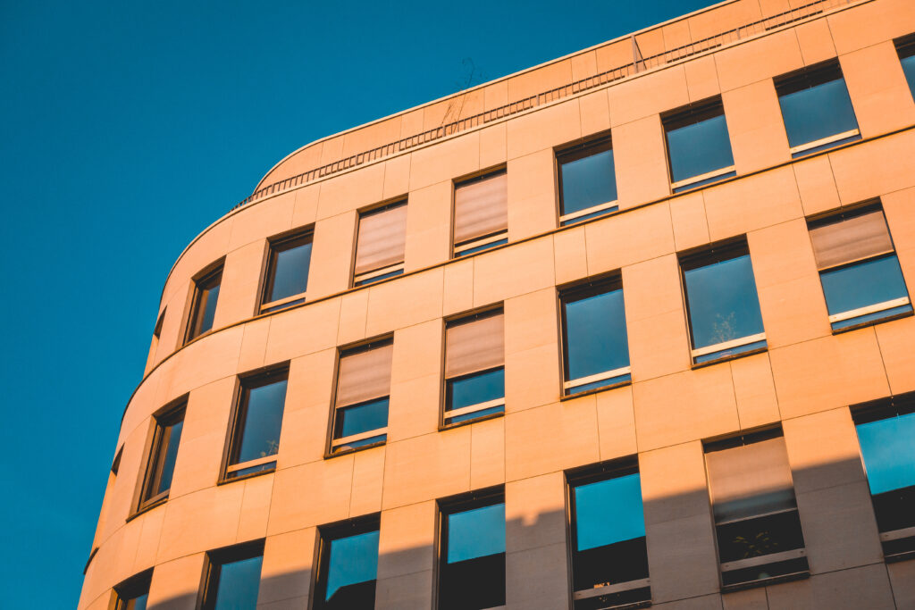 Modern curved art deco building with windows colored orange from the sunset with bright blue sky