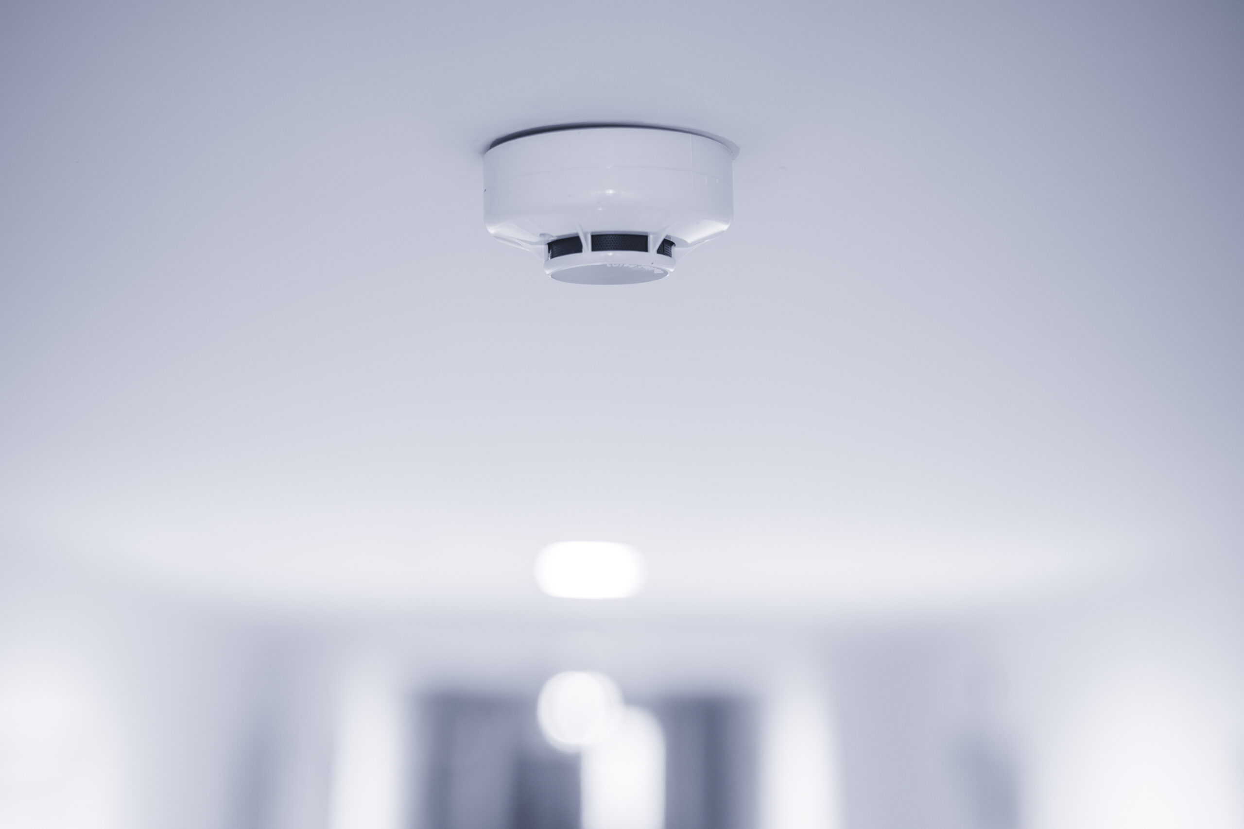 White smoke detector mounted on a white ceiling